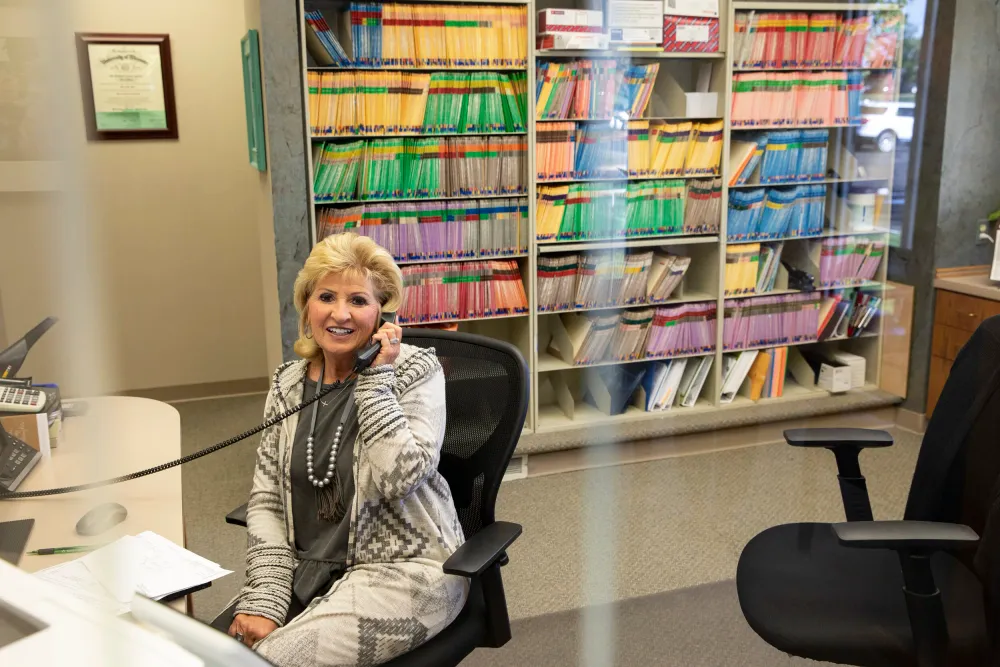 A front-desk staff member on the phone at the reception desk.