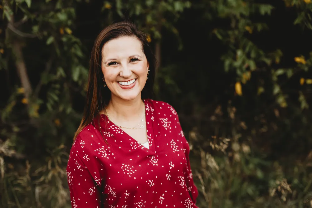 Dr. Megan Dosch &mdash; outdoor portrait in a red blouse.